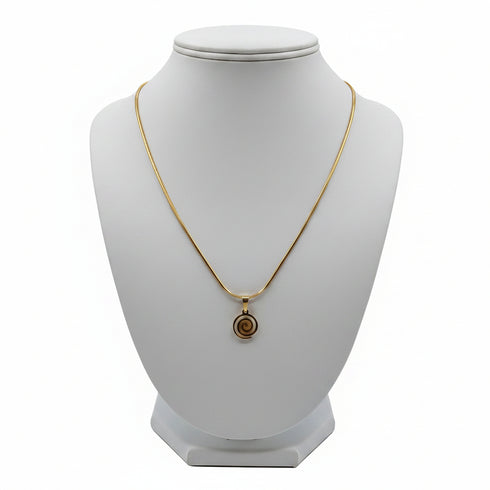 Gold necklace with a spiral pendant on a marble surface