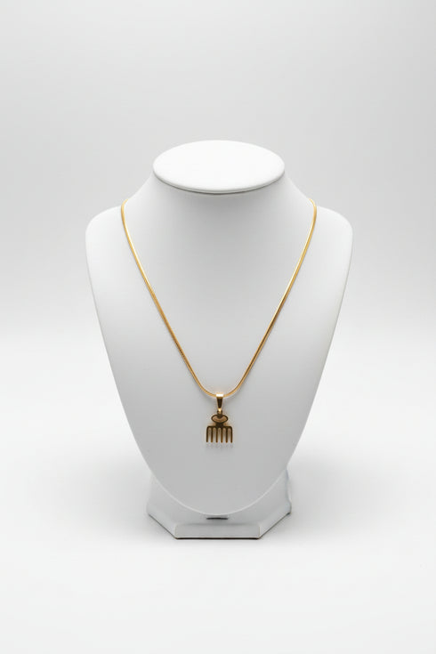 Gold hairpin with decorative end on a marble surface