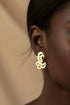 Decorative metal earrings on a textured beige background
