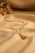 Gold necklace with a comb-shaped pendant on a marble surface