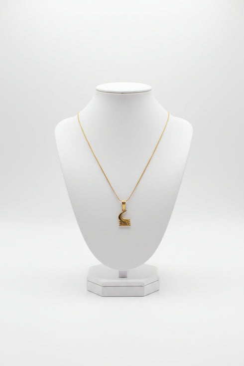 Gold necklace with a unique pendant on a marble surface