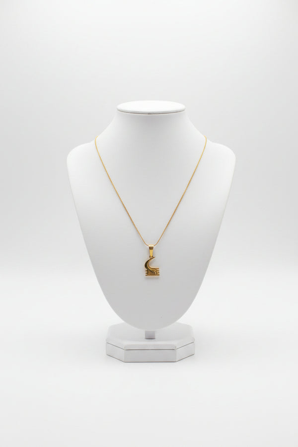 Gold necklace with a unique pendant on a marble surface