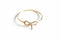 Gold bow-shaped bracelet on a marble surface