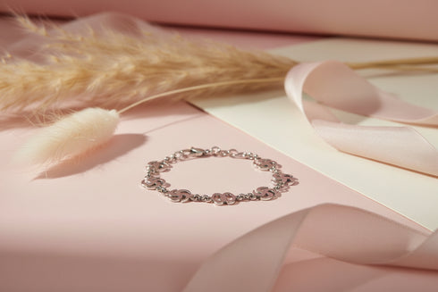 Silver bracelet on a soft pink surface with decorative elements
