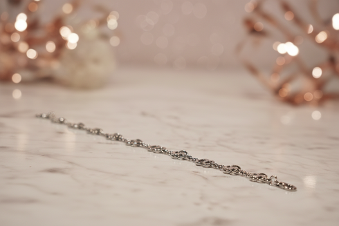 Silver bracelet on a marble surface with blurred decorative lights in the background