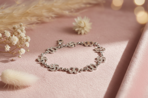 Silver bracelet on a pink surface with dried flowers