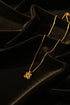 Gold necklace with a floral clasp on a marble surface