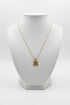 Gold necklace with a four-leaf clover pendant on a marble surface