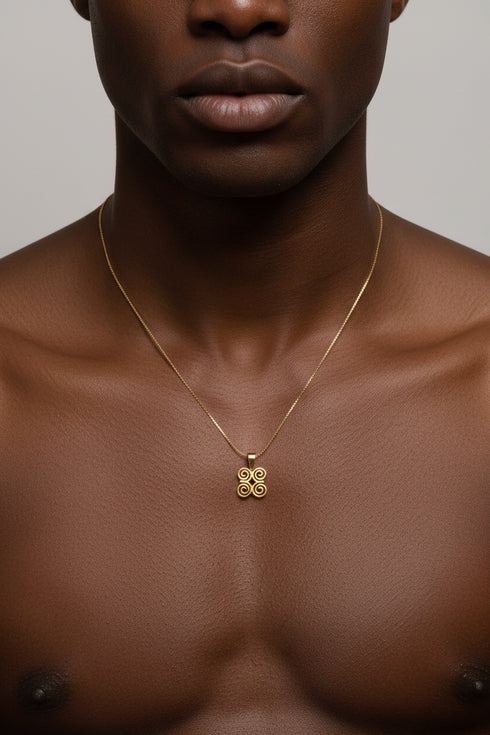Gold necklace with a four-leaf clover pendant on a marble surface