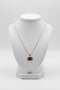 Gold necklace with a pendant on a white mannequin bust against a white background