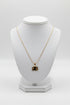 Gold necklace with a pendant on a white mannequin bust against a white background