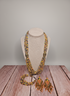 Beaded necklace and earrings set on a mannequin bust with a wooden surface and gray background