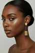 Gold earrings with black stones on a marble surface
