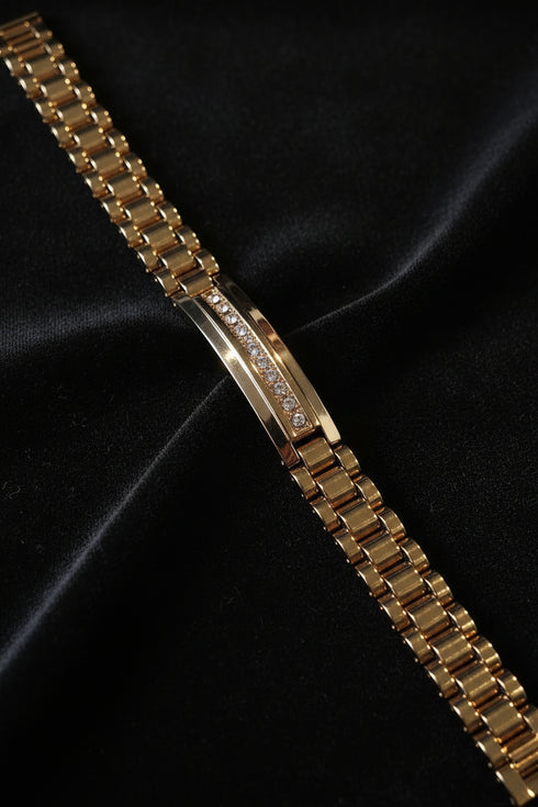 Gold bracelet with diamond accents on a black satin background