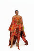 A woman modeling a vibrant red halter dress with a bold circular pattern in orange, yellow, green, and brown, styled with white sneakers against a plain white background.