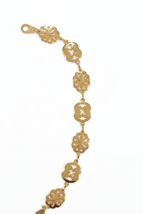 Gold bracelet with floral designs on a marble surface