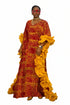 A woman modeling a long red and yellow patterned kaftan dress with dramatic ruffled sleeves, standing in front of a black and white striped wall.