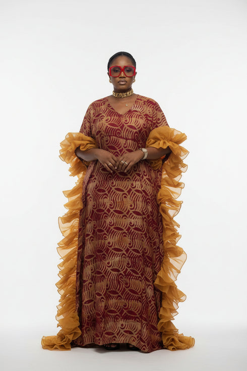 A woman modeling a traditional patterned dress with yellow ruffled sleeves and red sunglasses, standing in front of a striped gray background. The image is a screenshot from a social media post with text overlays and commerce icons.