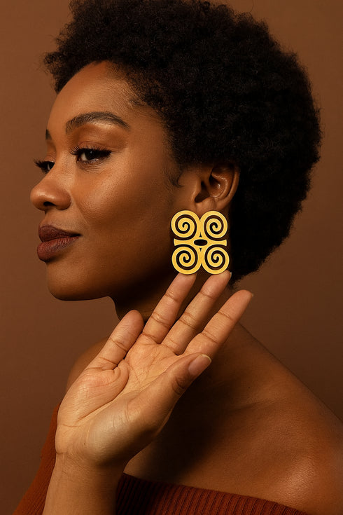 Woman wearing gold earrings with a brown background