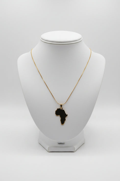 Gold necklace with a leaf-shaped pendant on a marble surface
