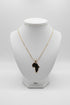 Gold necklace with a leaf-shaped pendant on a marble surface