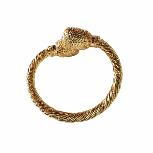 Gold bracelet with a textured design on a white background