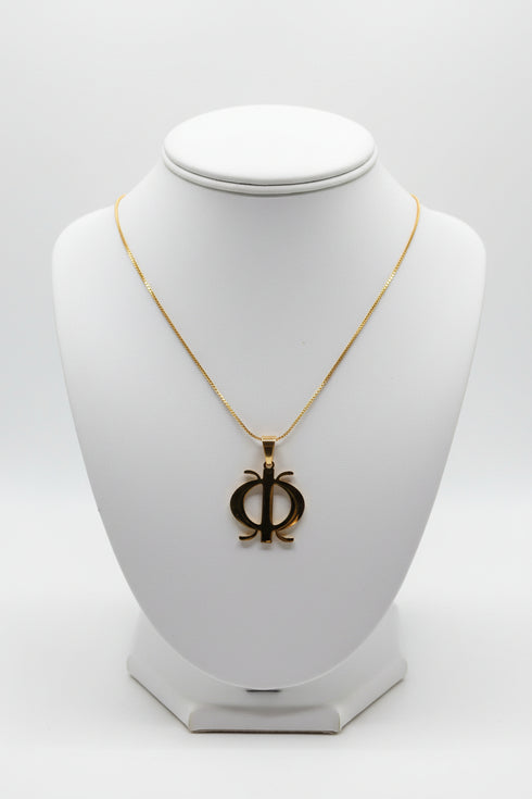 Gold necklace with a unique pendant on a marble surface