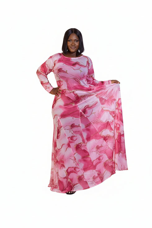 A woman modeling a long-sleeved maxi dress with a pink and white abstract watercolor pattern, standing against a plain white studio background.
