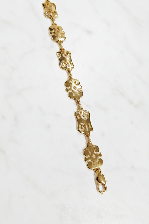 Gold bracelet with decorative links on a marble surface