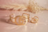 Gold bracelet and ring set on a soft pink background with dried flowers.