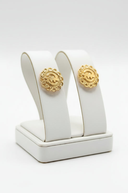 Gold earrings on a white stand with a white background