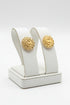 Gold earrings on a white stand with a white background