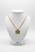 Gold chain necklace with a square pendant on a marble surface
