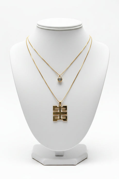 Gold necklace with a gold pendant on a marble surface