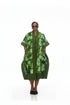 A woman modeling a green patterned kaftan dress with short sleeves, pockets, and a high collar, standing against a plain white background.