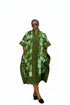 A woman modeling a green and white patterned kaftan dress with a high collar, short sleeves, and front pockets, set against a plain white background.