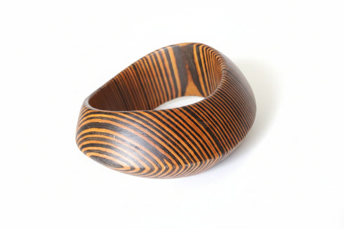 Wooden bracelet with striped pattern on a marble surface