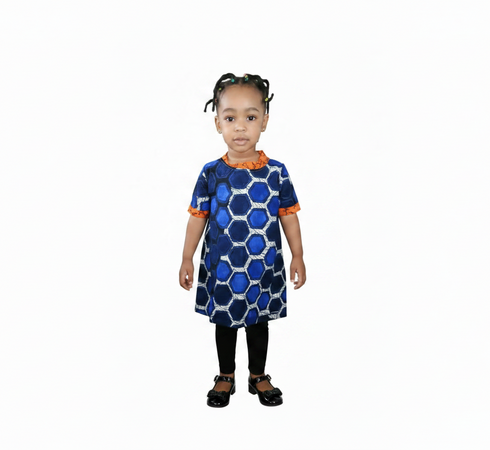 A young child standing against a plain white background, wearing a short-sleeve blue dress with a geometric hexagon pattern and orange trim, paired with black leggings.