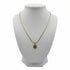 Gold necklace with a spiral pendant on a marble surface