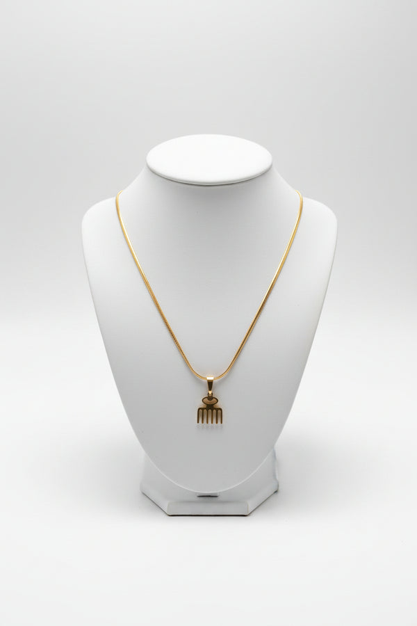 Gold hairpin with decorative end on a marble surface