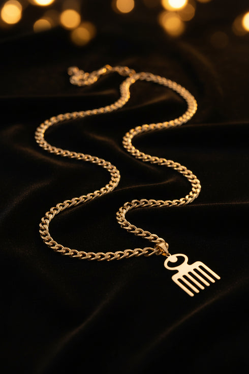 Gold chain with a fork-shaped pendant on a marble surface