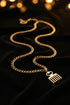 Gold chain with a fork-shaped pendant on a marble surface