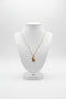 Gold necklace with a unique pendant on a marble surface