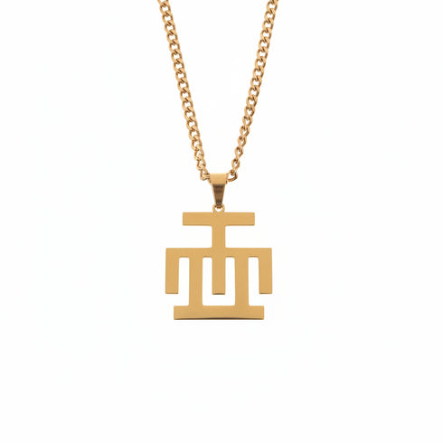 Gold necklace with a geometric pendant on a marble surface