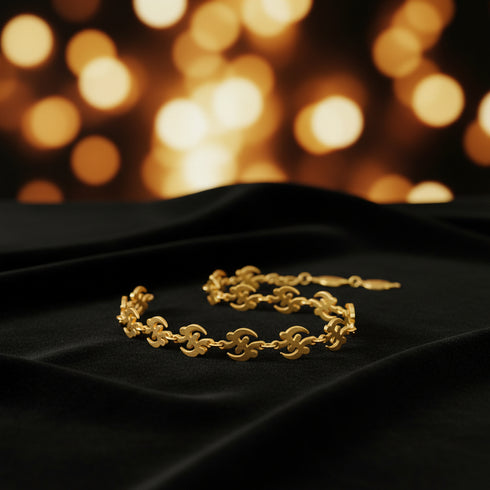 Gold bracelet with floral designs on a marble surface