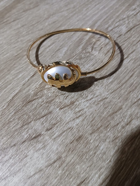 Gold bracelet with a decorative clasp on a wooden surface