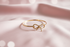 Gold bracelet with bow design on a soft pink fabric background