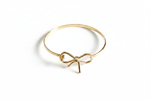Gold bow-shaped bracelet on a marble surface