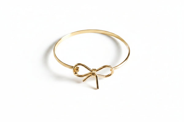 Gold bow-shaped bracelet on a marble surface