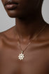 Gold necklace with a star-shaped pendant on a marble surface